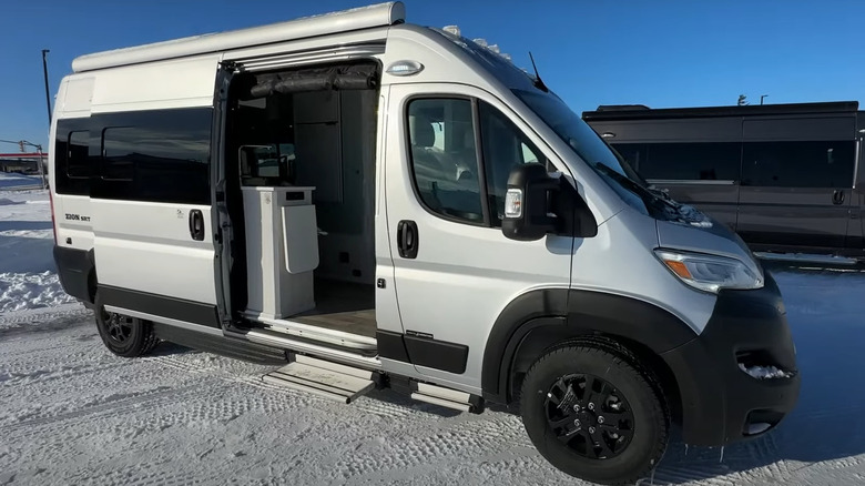A silver Roadtrek Zion parked in a snowy field, with its sliding door open