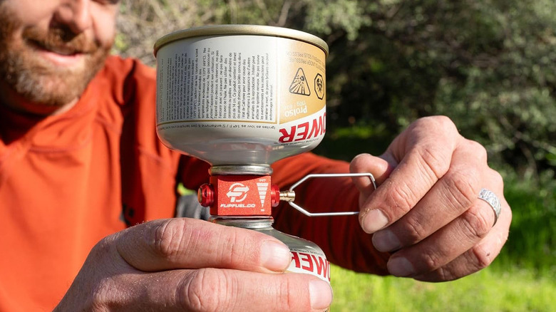 A camper transferring fuel between canisters using the FlipFuel Fuel Transfer Device.