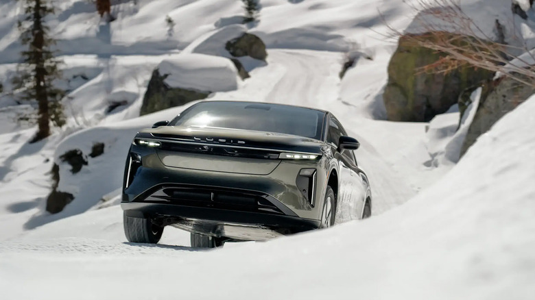 A gray Lucid Air climbing a snowy road on a hillside