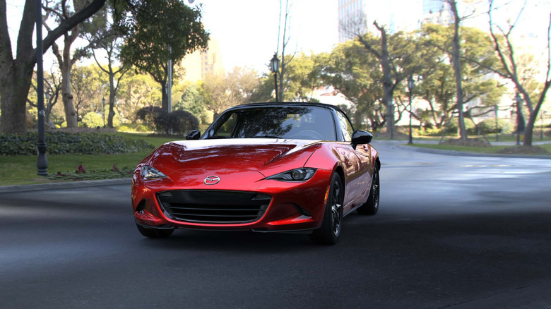 A red Mazda Miata MX-5 parked on a tree-lined street