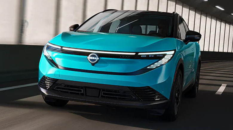 A teal Nissan Leaf driving in a tunnel