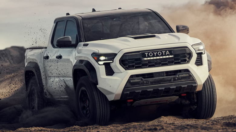A white Toyota Tacoma driving recklessly in the dirt