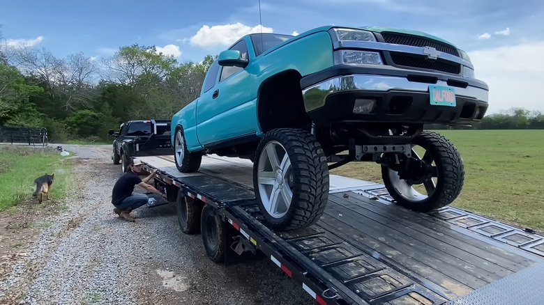 Cody Detwiler, known online as "Whistlin Diesel," looking up at a blue pickup truck that has the Carolina Squat