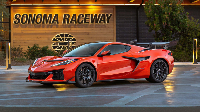 An orange 2026 Corvette parked sideways in front of the main entrance to the Sonoma Race Circuit.
