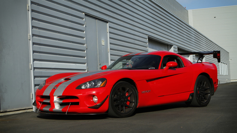 An orange Dodge Viper standing next to what appears to be garage doors on a race track pit lane.