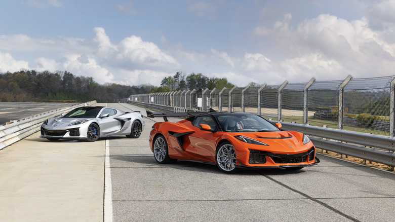 Two Chevrolet Corvette ZR1X models for the 2026 year parked next to each other on a racetrack, finished in Sebring Orange and Blade Silver.