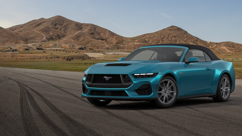 A light metallic blue 2026 Ford Mustang, shown here in its Convertible, open-top body style parked at an angle on a road.