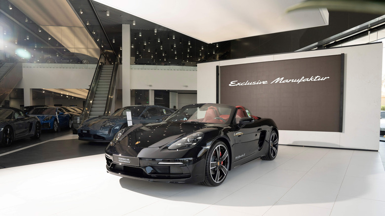 A black Porsche 718 Boxster Manufaktur edition parked on a viewing podium at a Porsche showroom in Riyadh, Saudi Arabia.