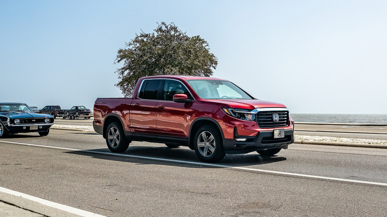A wine Honda Ridgeline driving beside a coastline