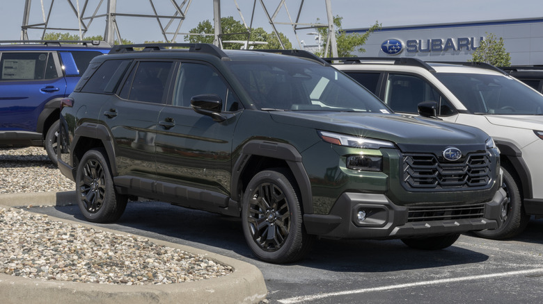 A dark green Subaru outback at a Subaru dealership