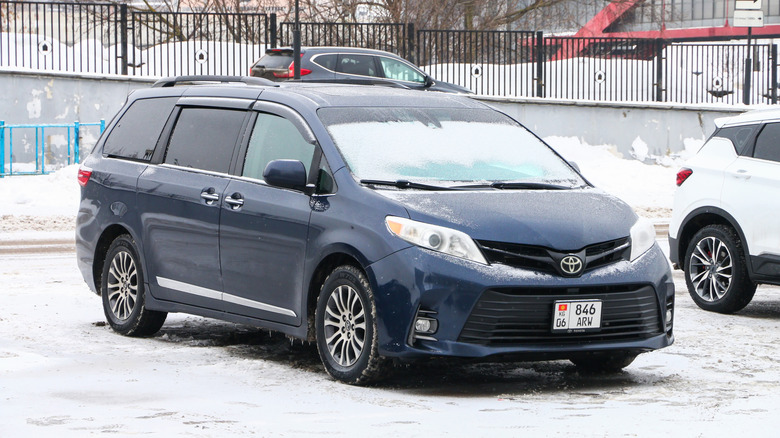 A blue Toyota Sienna with ice outlining the windows and tires