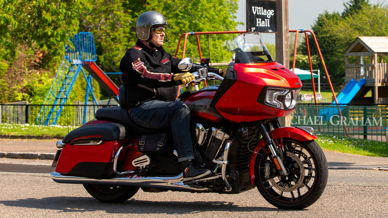 A red 2021 Indian Challenger motorcycle in the Limited trim moving through an English village in the U.K.