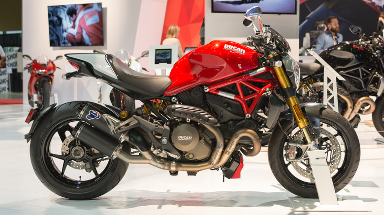 A red and black 2015 Ducati Monster 1200S on display on a podium at an indoor show.