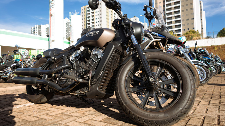 An all-black Indian Scout bobber motorcycle parked on a stone-paved road.