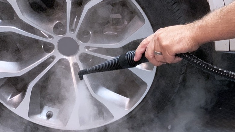 Person cleaning tire with steamer