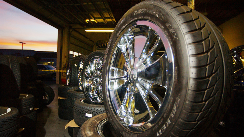 Chrome aftermarket wheels with Falken tires stacked inside a tire shop at sunset.