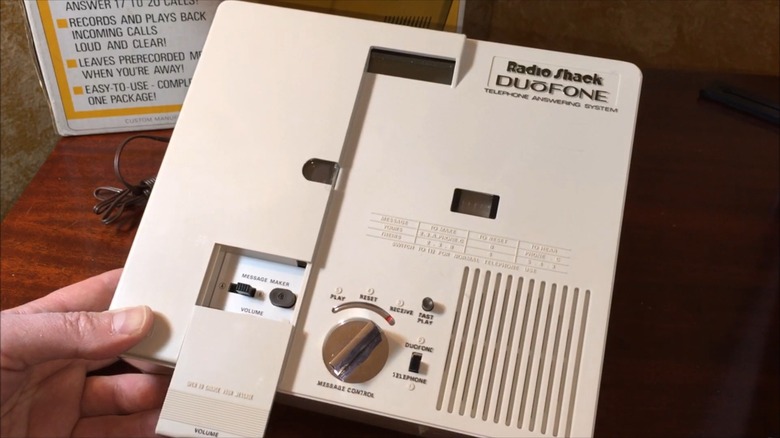 A man's hand showing off the Duōfone Telephone Answering System's hidden control compartment