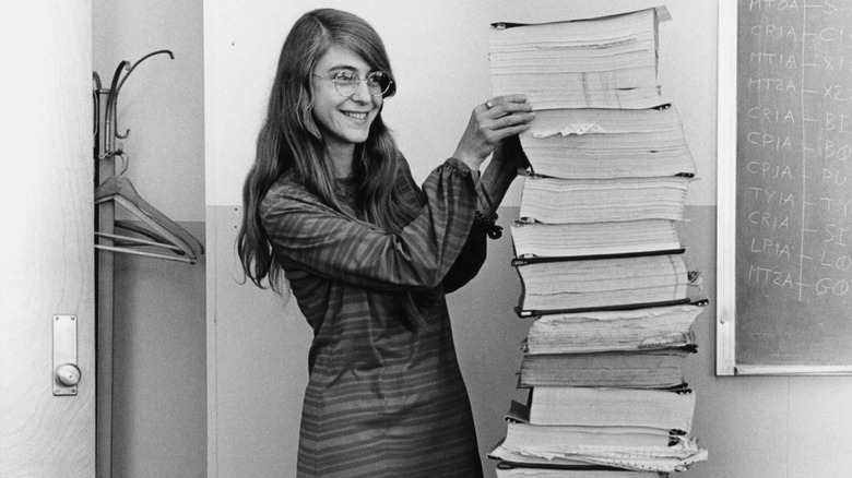 Margaret Hamilton standing next to listings of the software that she and her MIT team produced for the Apollo Project.