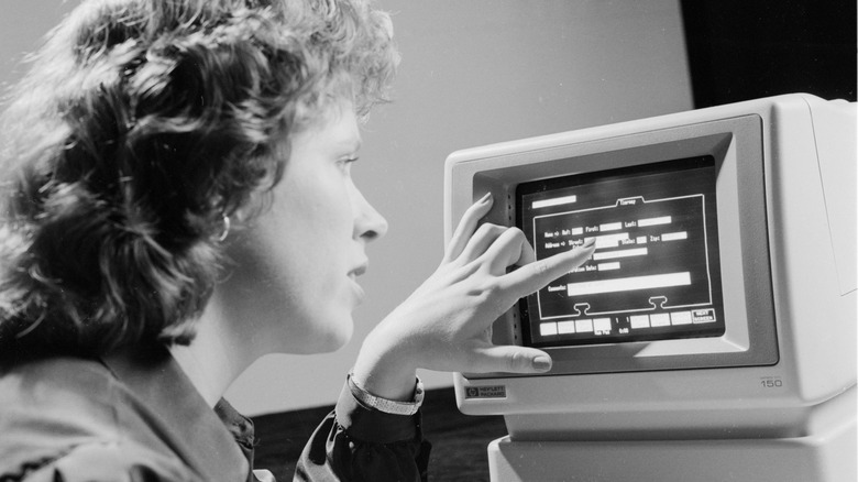 A woman interacting with an HP 150 PC's touchscreen in the early 1980s