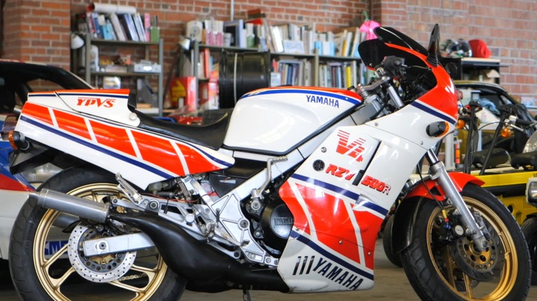 An image of a person sitting on an RZV500R, son image of a person sitting on an RZV500R in his garage, taking in its greatness, with books lining the background.aking in its greatness, in his garage that has books at the background.
