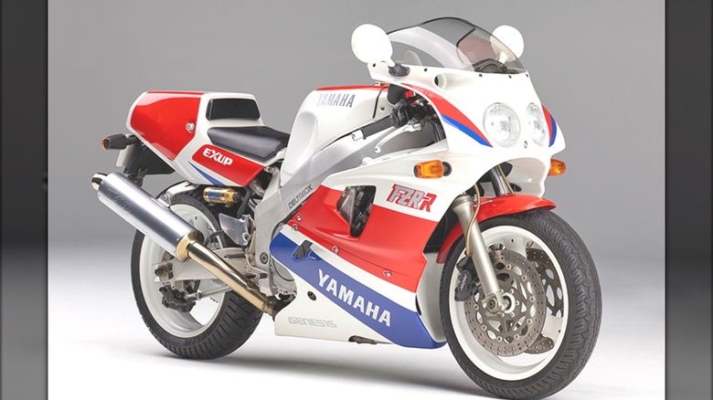 An image of the red and white Yamaha FZR750R (OW01) with subtle purple accents, set against a plain background.