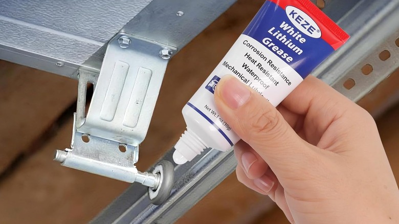 A hand squeezing lubricant onto a garage hinge.