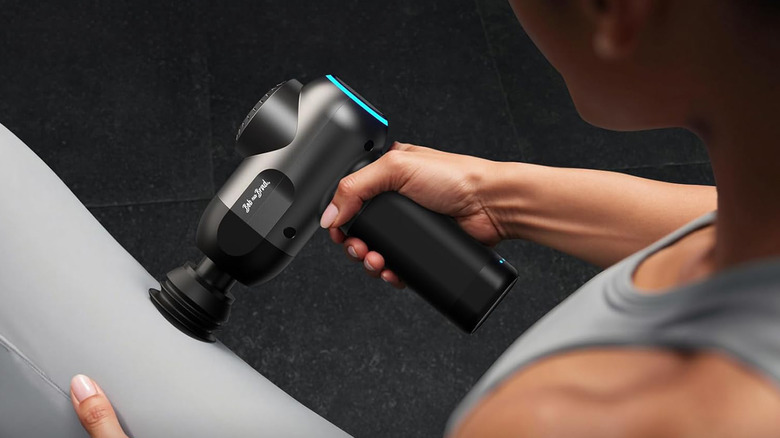 A woman using a Bob and Brad C2 gun to massage her thigh