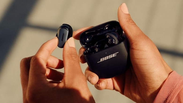 A gold pair of Bose QuietComfort Ultra Earbuds against a black background