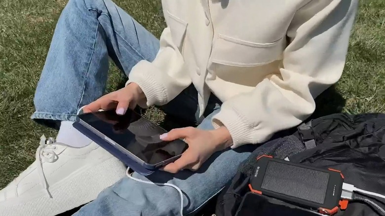 Person using solar power bank with tablet