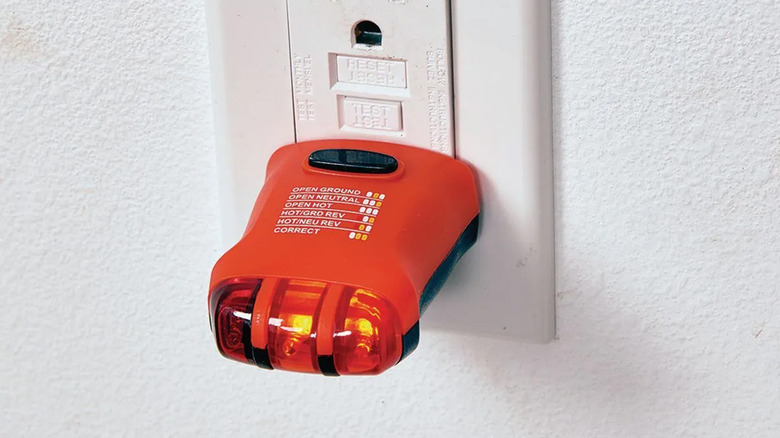 An Ames Instruments brand outlet tester plugged in a wall socket.