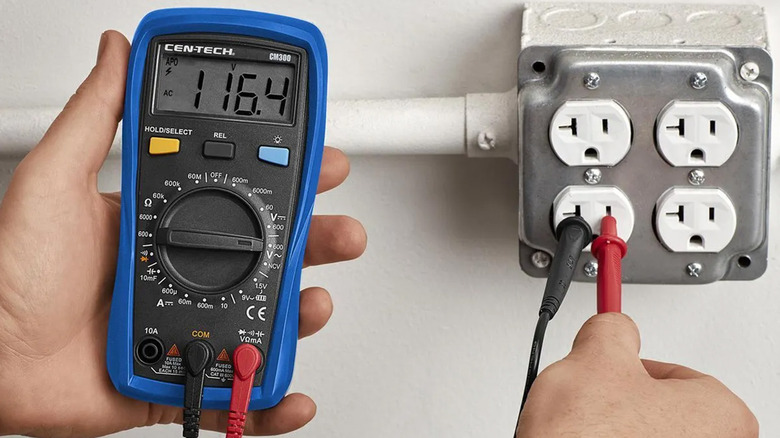 A person using a CEN-Tech multimeter to test an outlet.