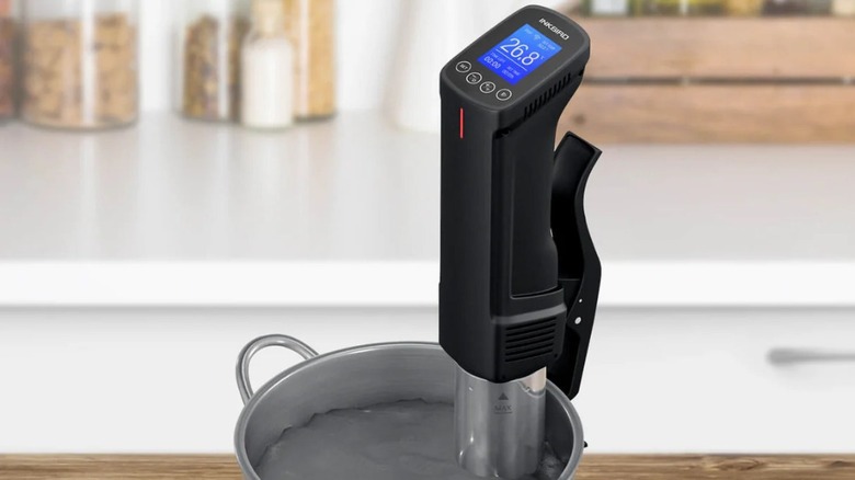 An Inkbird sous vide cooker with rows of meat immersed in it, reading 135 degrees Fahrenheit