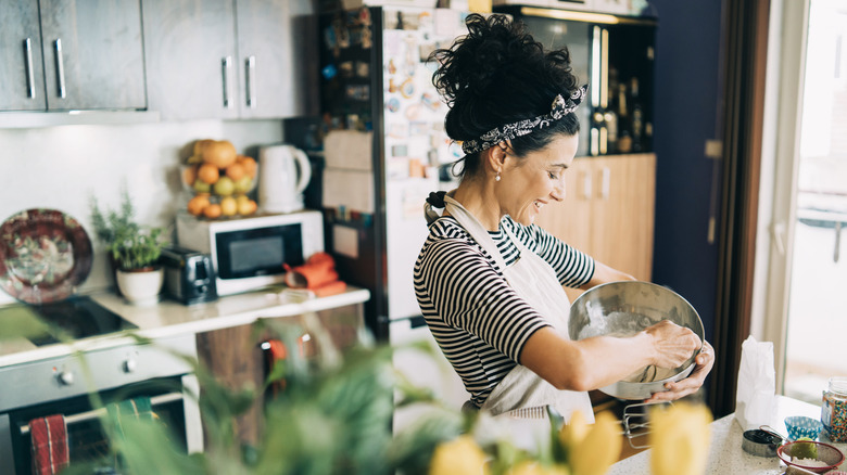 A woman smiling as she operates a kitchen gadget