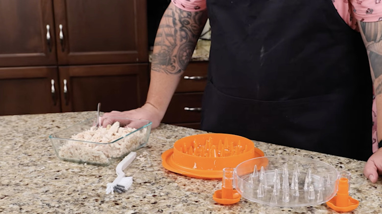 A red Suretivian chicken shredder on a countertop