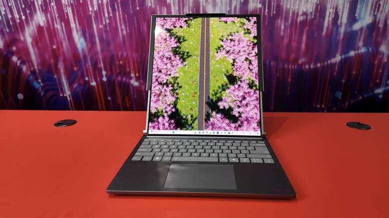 A Lenovo ThinkPad Rollable laptop sitting on a red table with the display fully extended vertically.