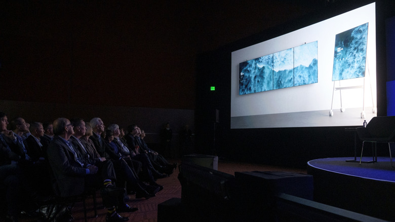 Board members watching a demo for the Microsoft Surface Hub 2 in a dark room.