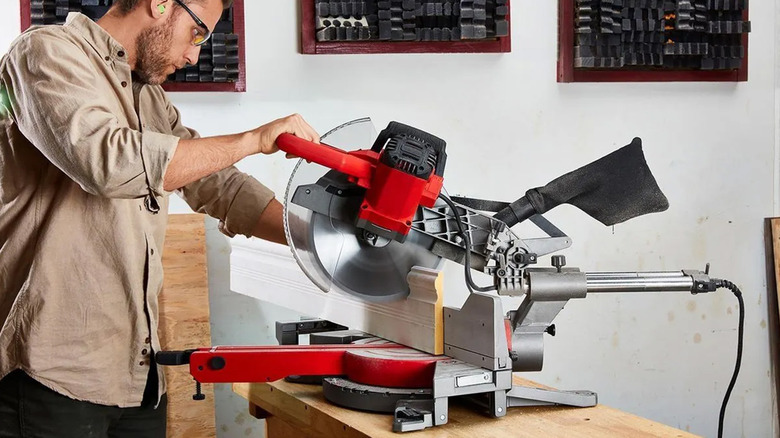 A man using a Bauer miter saw to cut wood.
