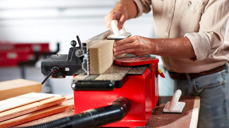 A person out of frame pushing a piece of wood across a Bauer jointer.