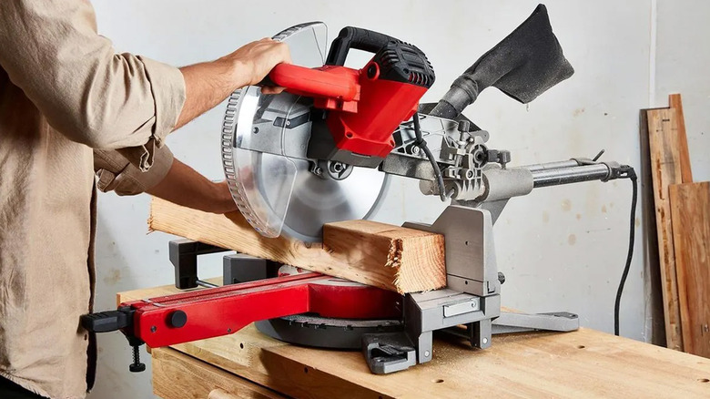 A person cutting wood with a Bauer miter saw in a shop.