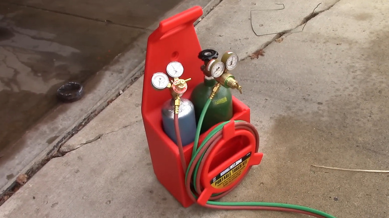 The Olsen Portable Oxygen and Acetylene Torch Kit on a cracked driveway.