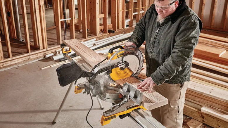A man using a miter saw to cut a piece of wood.