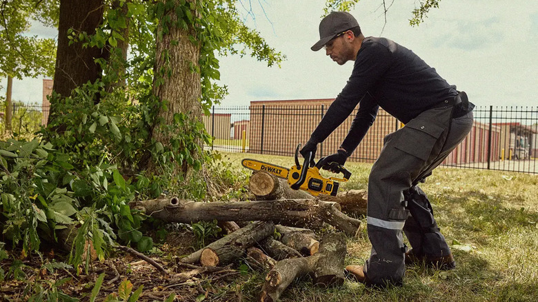 A man cutting logs with a DeWalt chainsaw.
