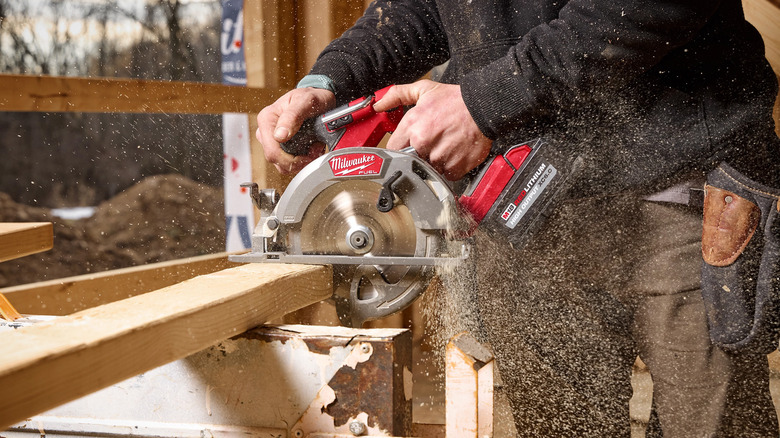 A person using a circular saw to cut pieces of wood.