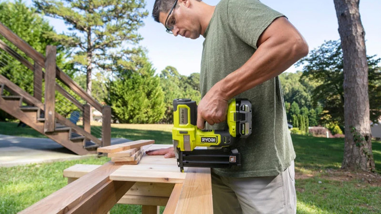 A man using a brad nailer to join pieces of wood together.