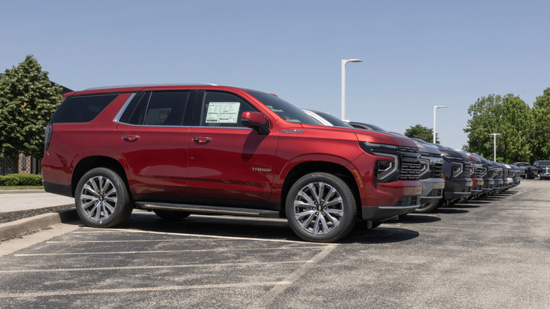 A current-gen 2024 Chevrolet Tahoe in red, parked in a lot with the right side view visible.