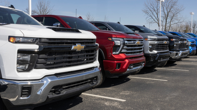 A line of differently-colored and specced Chevrolet Silverado 2500 trucks at a dealer.