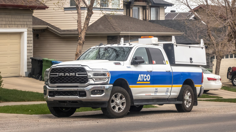 A dodge RAm 2500 with blue and white decals parked at the side of a suburban street.