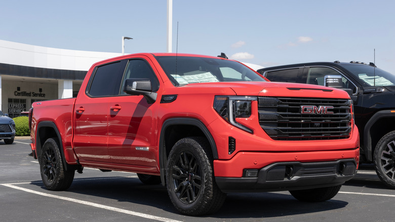 A Red GMC Sierra 1500 for the 2024 model year on display outside a dealer.