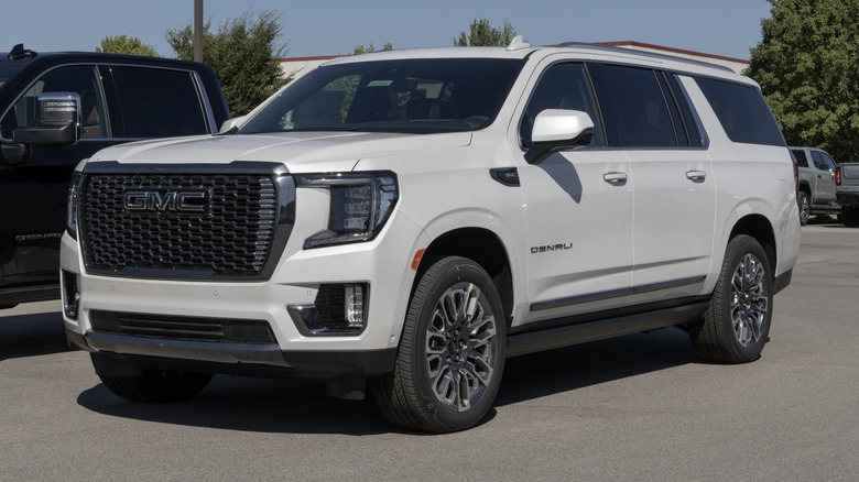 A whtie 2025 GMC Yukon with minimal chrome standing in a dealership parking lot.