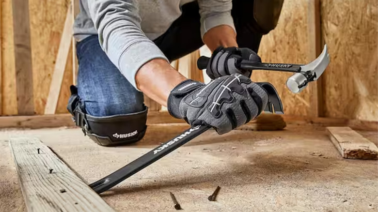 A worker hitting a crowbar with a hammer.